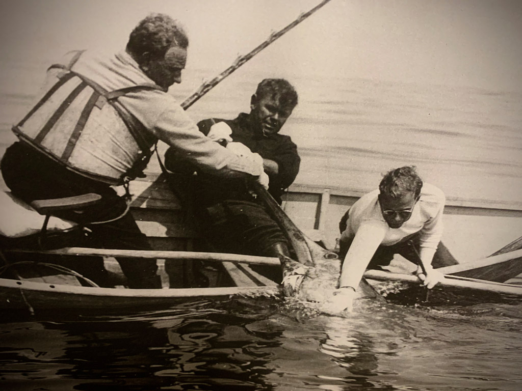 men on canoe pulling in swordfish
